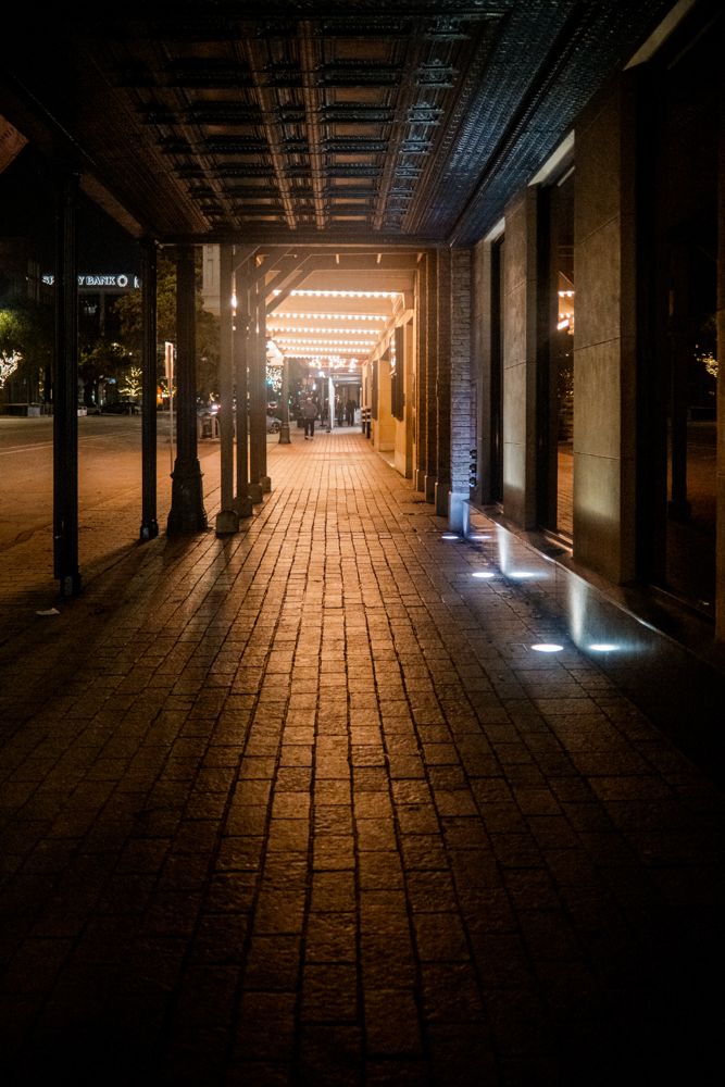 Night arcade in Austin, brick underfoot, lit colonnade receding